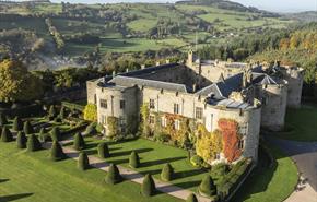 An aerial view of Chirk Castle and garden in autumn with the Virginia Creeper ivy climbing the castle walls and the garden path lined with shaped topi